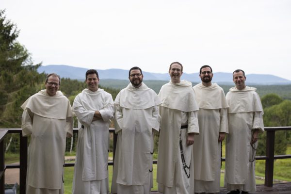 Six Dominicans stand in a line against a wooded backdrop in the Catskill mountains